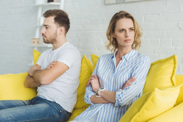 Upset couple sitting on yellow couch after argue — Stock Photo