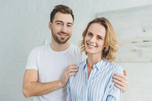 Junger lächelnder Mann umarmt Freundin im Zimmer mit Wandgemälde — Stockfoto