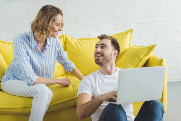 Sorrindo casal falando e sentado com laptop — Fotografia de Stock