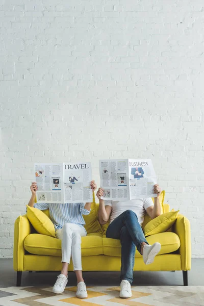 Empresário com namorada sentada no sofá e lendo jornais sobre viagens e negócios — Fotografia de Stock