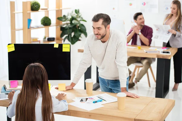 Selective focus of multicultural marketing managers at workplace and colleagues behind in office — Stock Photo