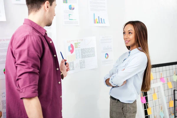 Multiethnic business colleagues at white board with papers in office — Stock Photo