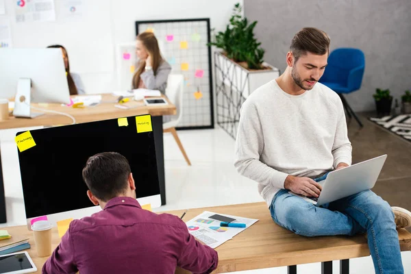 Selective focus of young businessmen at workplace and multicultural businesswomen in office — Stock Photo