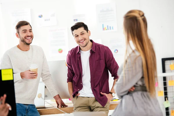 Foyer sélectif des hommes d'affaires souriants ayant une conversation avec la femme d'affaires au bureau — Photo de stock