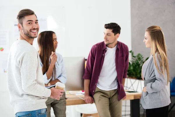 Focalizzazione selettiva dell'uomo d'affari sorridente e del gruppo di giovani colleghi d'affari multirazziali alla moda in carica — Foto stock