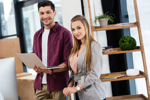 Retrato de gerentes de marketing sonrientes con computadora portátil en la oficina - foto de stock