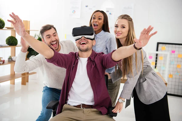 Fröhlicher Geschäftsmann im vr-Headset mit multikulturellen Kollegen in der Nähe im Büro — Stockfoto