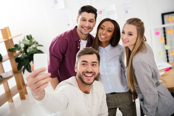 Happy multicultural business people taking selfie on smartphone together in office — Stock Photo