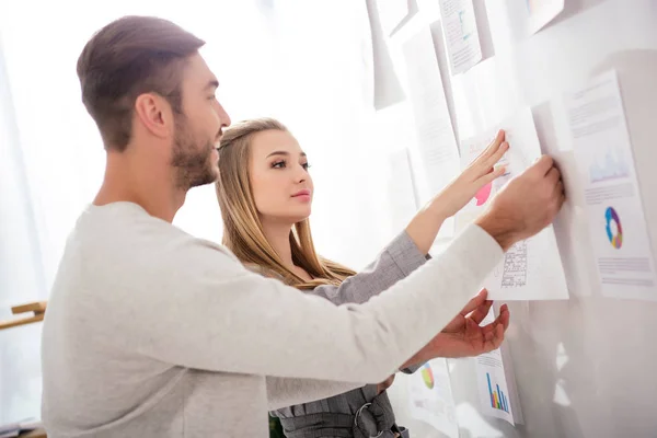 Business colleagues putting document at white board with papers in office — Stock Photo