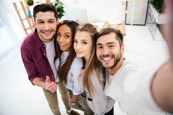 Ponto de vista câmera de empresários multiculturais felizes tomando selfie juntos no escritório — Fotografia de Stock