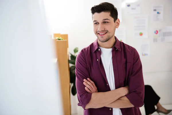 Enfoque selectivo del gerente de marketing sonriente con los brazos cruzados en la oficina - foto de stock