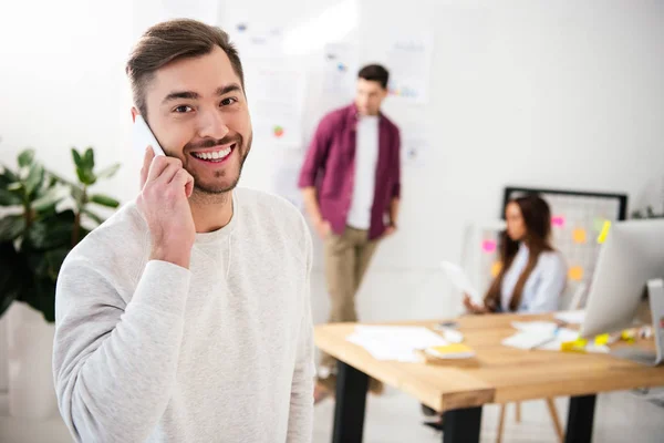 Focalizzazione selettiva di un uomo d'affari sorridente che parla sullo smartphone in ufficio — Foto stock