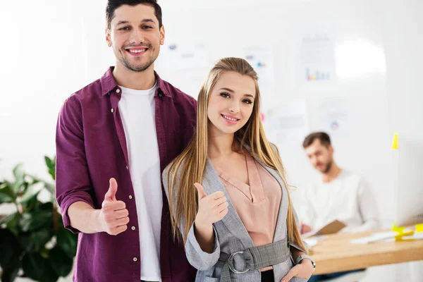 Portrait of young marketing managers in office showing thumbs up — Stock Photo