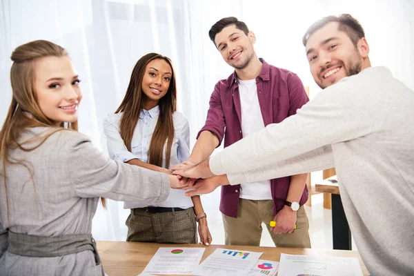 Multicultural group of marketing managers holding hands together in office, teamwork concept — Stock Photo