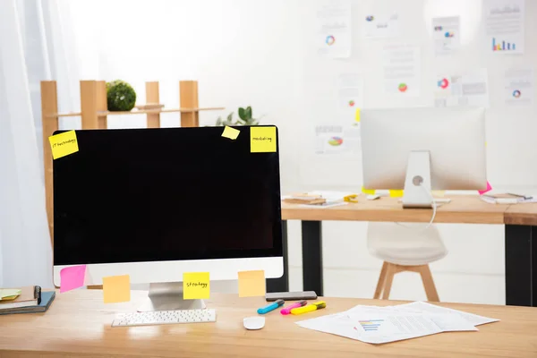 Close up view of workplace with blank computer screen, sticky notes and papers in office — Stock Photo