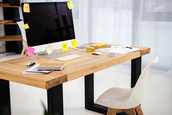 Close up view of workplace with blank computer screen, sticky notes and documents in office — Stock Photo