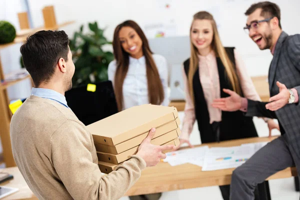 Enfoque selectivo de hombre de negocios trajo pizza para colegas multiétnicos en el cargo - foto de stock