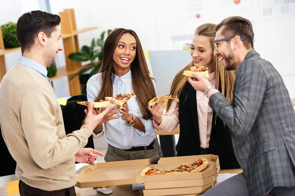Retrato de gente de negocios multiétnicos comiendo pizza juntos en la oficina - foto de stock