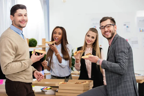 Retrato de gente de negocios multiétnicos comiendo pizza juntos en la oficina - foto de stock