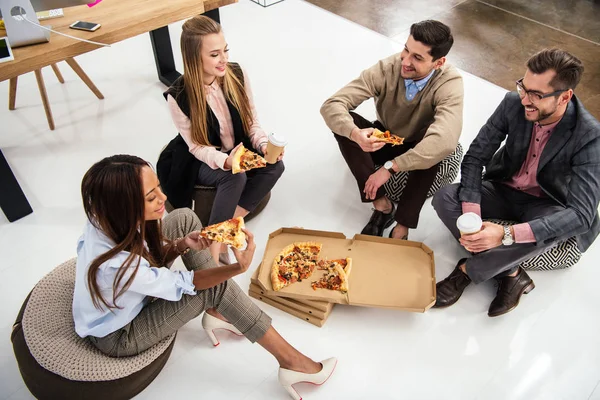 High angle view of multiethnic business people eating pizza in office — Stock Photo