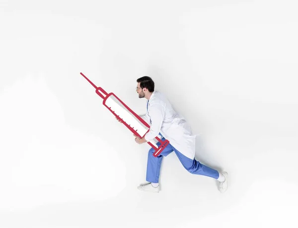 Colagem criativa de bonito jovem médico correndo e segurando seringa desenhada — Fotografia de Stock