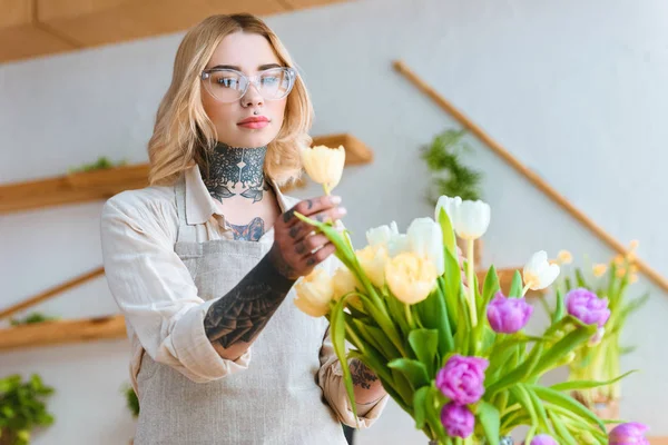 Giovane fiorista donna in occhiali da vista che lavora con bellissimi tulipani — Foto stock