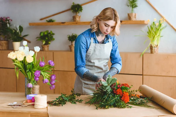 Attraktive junge Floristin arrangiert Blumen im Blumenladen — Stockfoto