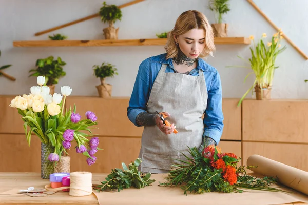 Schöne junge Frau arrangiert Blumen im Blumenladen — Stockfoto