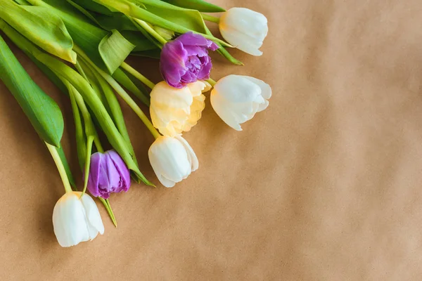 Vista superior de hermosas flores de tulipán sobre papel artesanal - foto de stock