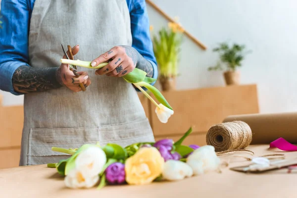 Cortado tiro de florista em avental cortando flor de tulipa — Fotografia de Stock