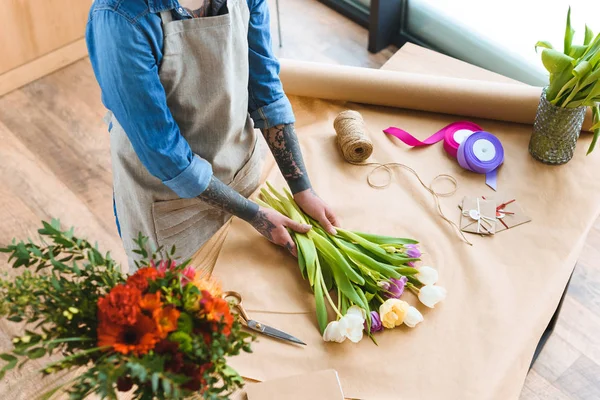Обрезанный снимок флориста в фартуке, работающего с красивыми цветами тюльпана — стоковое фото