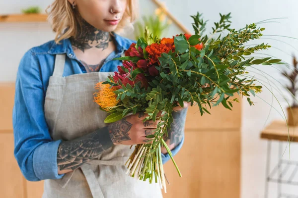 Plan recadré de jeune fleuriste avec des tatouages tenant bouquet de fleurs — Photo de stock