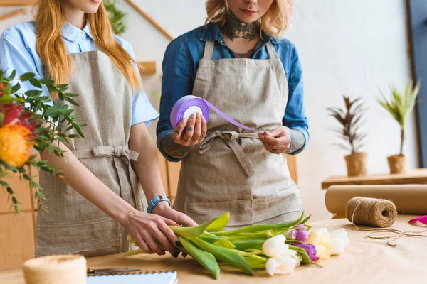 Cropped shot of young female florists arranging flower bouquet together — Stock Photo