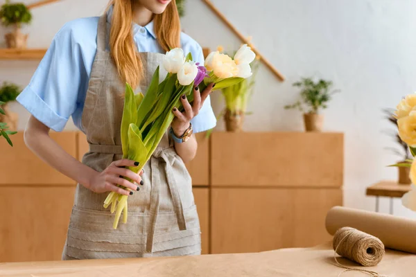 Plan recadré de fleuriste dans tablier tenant de belles tulipes sur le lieu de travail — Photo de stock