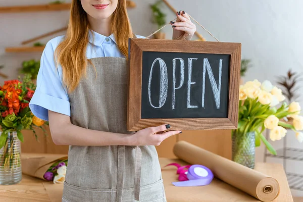 Cropped shot of smiling young florist in apron holding sign open — Stock Photo