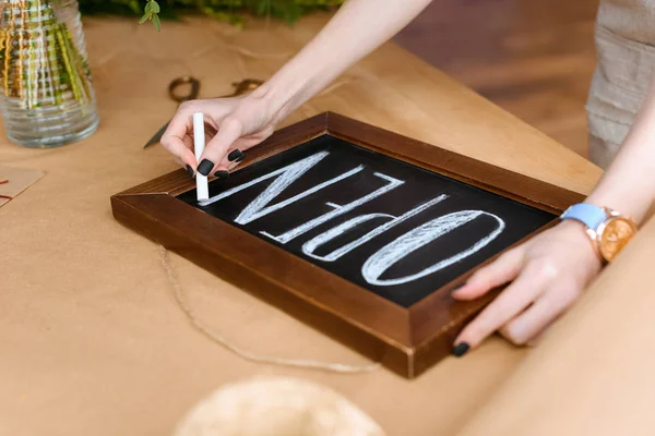 Close-up partial view of young florist writing word open with chalk on board — Stock Photo