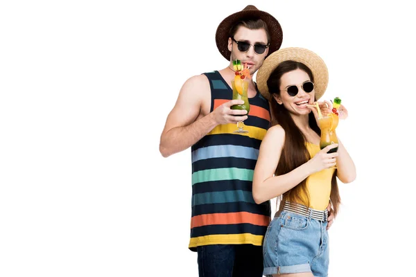 Casal alegre em óculos de sol e chapéus bebendo coquetéis de verão, isolado em branco — Fotografia de Stock