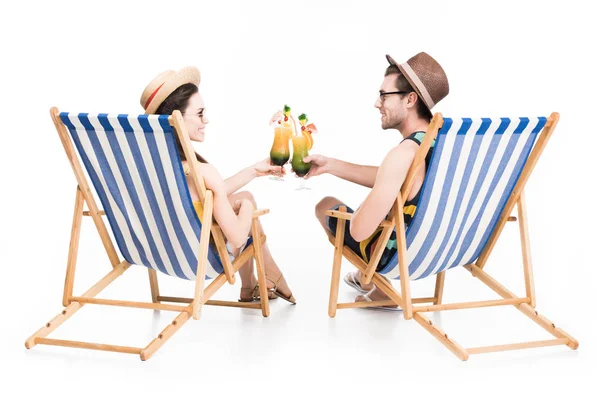 Paar sitzt auf Liegestühlen und klirrt mit Cocktailgläsern, isoliert auf weiß — Stockfoto