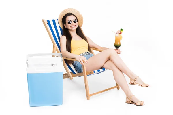 Красива дівчина відпочиває на пляжному стільці з коктейлем і прохолодною коробкою, ізольована на білому — стокове фото