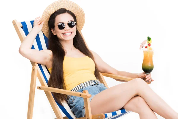 Приваблива дівчина, що розслабляється на пляжному стільці з коктейлем у склі, ізольована на білому — стокове фото