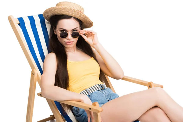 Красивая девушка в солнцезащитных очках, отдыхающая на пляжном шезлонге, изолированная на белом — стоковое фото