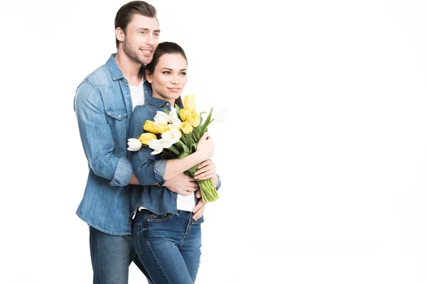 Homem feliz abraçando namorada com buquê de flores da primavera, isolado no branco — Fotografia de Stock