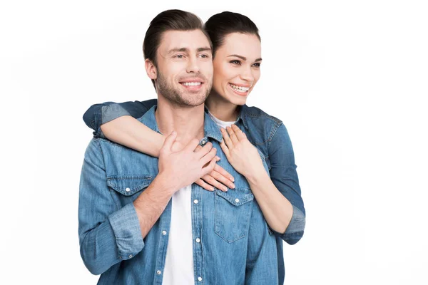 Joven sonriente pareja en denim ropa abrazo aislado en blanco - foto de stock