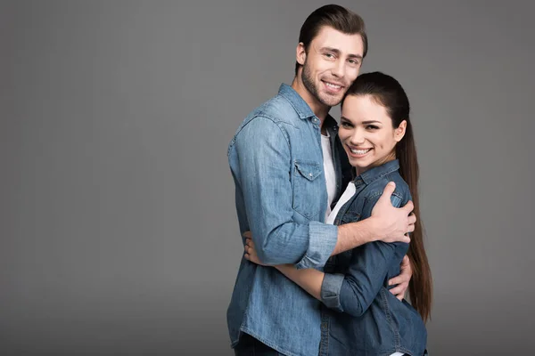 Fröhliches Paar umarmt sich vereinzelt auf grau — Stockfoto