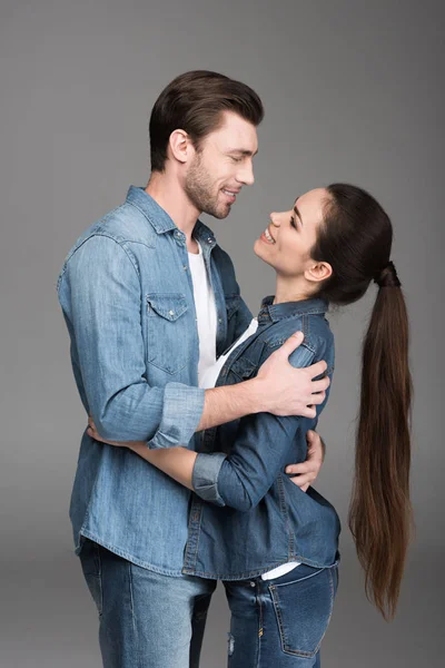 Lächelndes Paar, das einander umarmt und ansieht, isoliert auf grau — Stockfoto