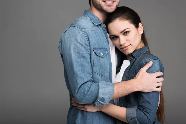 Young beautiful couple in jeans hugging isolated on grey — Stock Photo