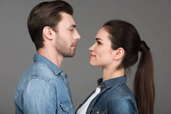Junges Paar schaut einander an, isoliert auf grau — Stockfoto