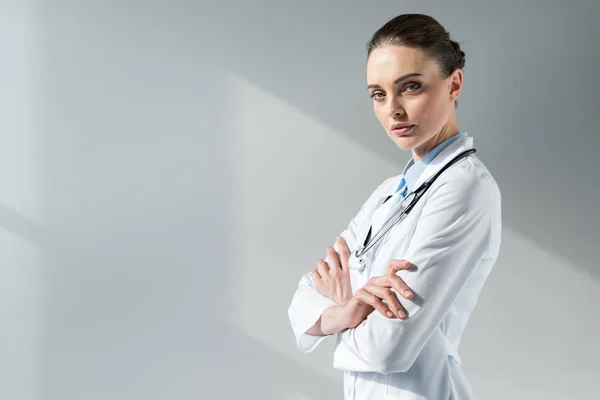 Confiada doctora con brazos cruzados mirando a la cámara - foto de stock