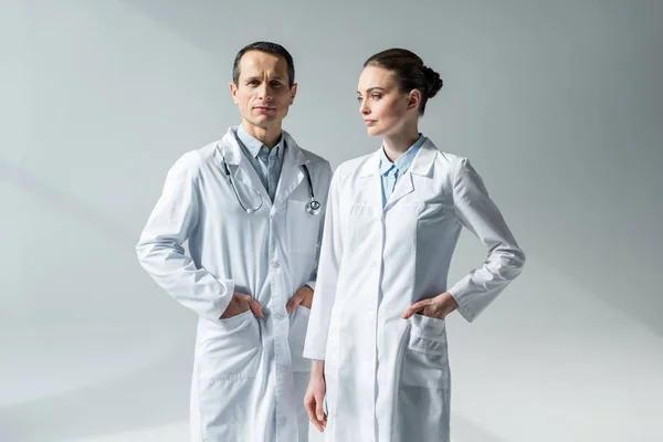 Médicos adultos confiantes em casacos brancos em cinza — Fotografia de Stock