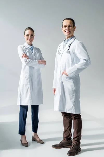 Zufriedene erwachsene Ärzte blicken auf Kamera auf weiß — Stockfoto